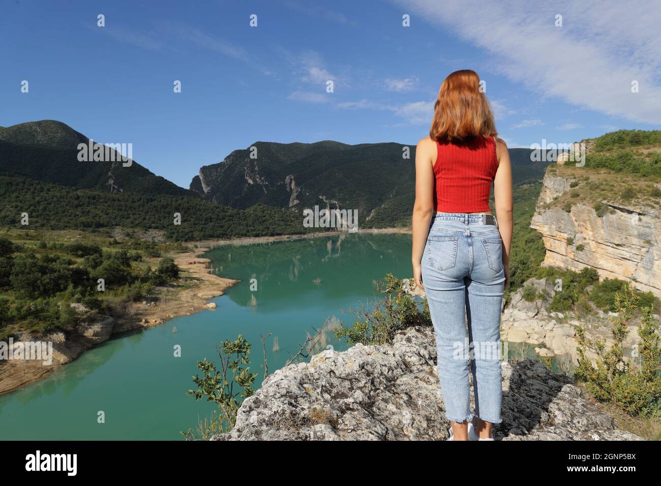 Rückansicht Ganzkörperportrait einer Frau in Rot, die einen See betrachtet Stockfoto
