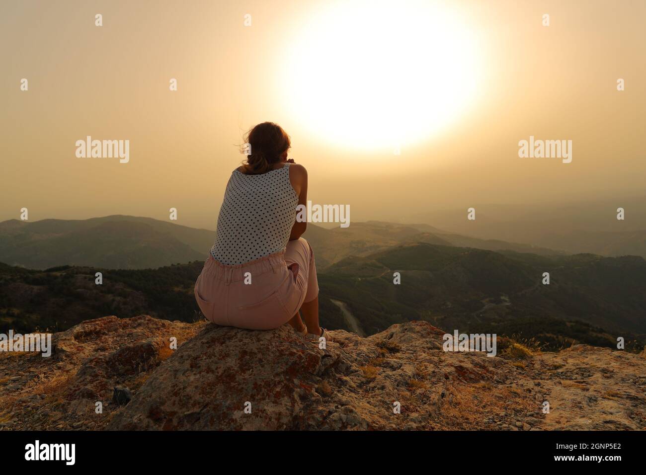 Rückansicht Porträt einer Frau, die allein den Sonnenuntergang im Berg betrachtet Stockfoto