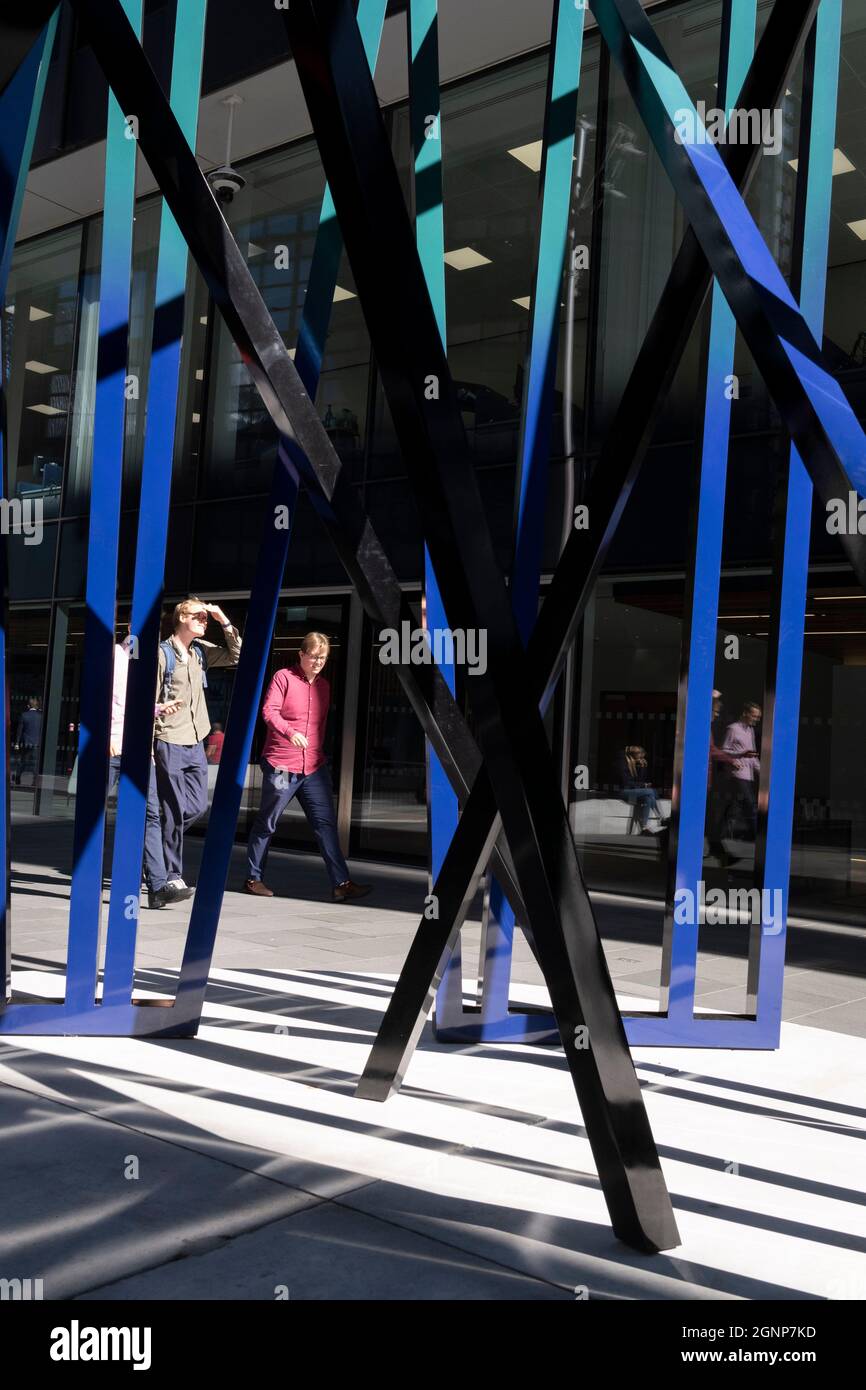 Stadtarbeiter gehen am 24. September 2021 in London, England, an der Skulptur „Cosmos“ vorbei, einem Kunstwerk von Eva Rothschild in der City of London, dem Finanzviertel der Hauptstadt. Cosmos (2019) besteht aus drei 3,5m hohen Lattenrost-Strukturen, die sich schlank und stützen und ist Teil des Sommerprojekts Art in the City. Stockfoto