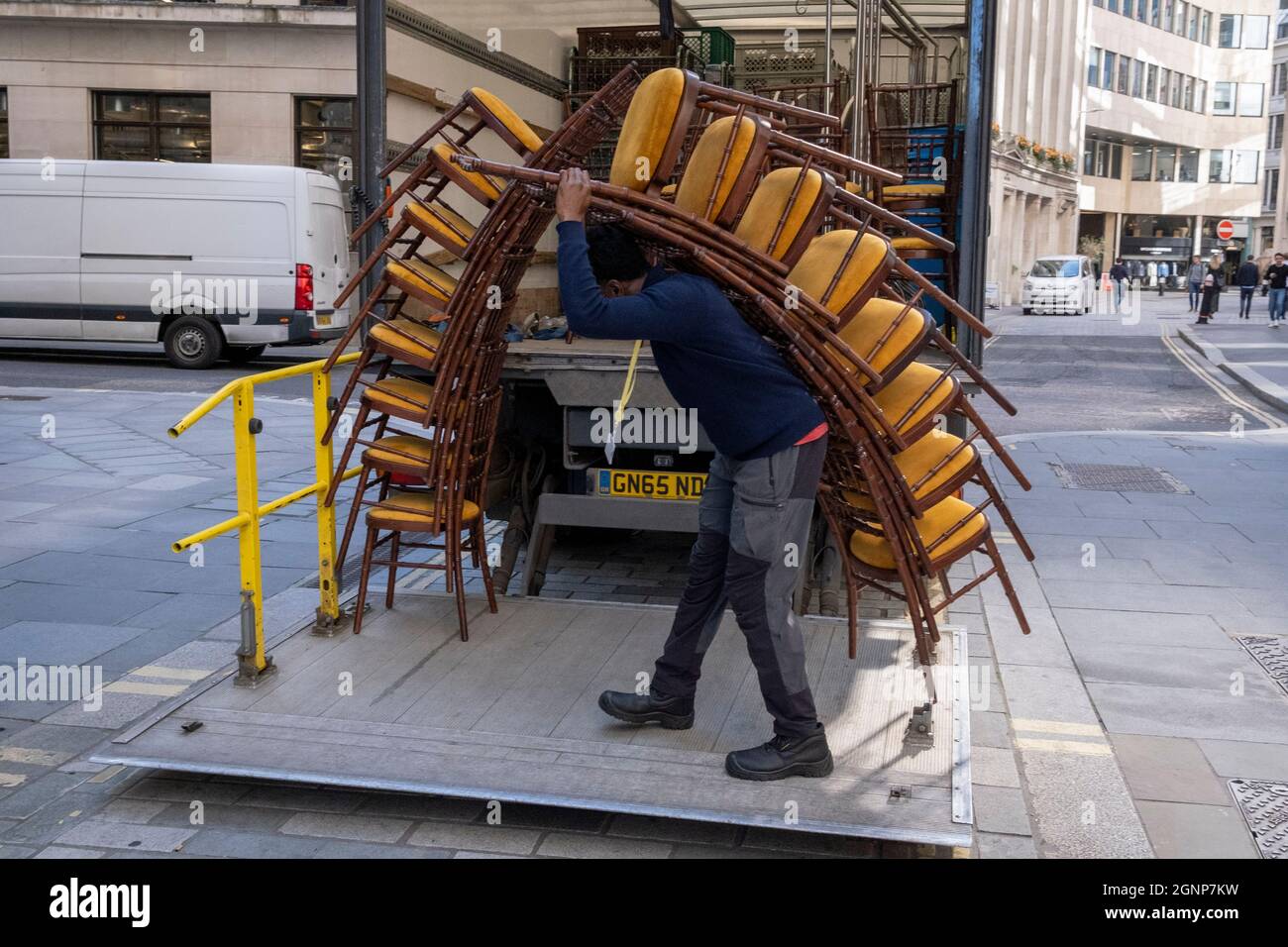 Nach einer Veranstaltung in Lloyds of London in der City of London, dem Finanzdistrikt der Hauptstadt, am 24. September 2021 in London, England, beladen Auftragnehmer des Möbelherstellers „Well dressed Tables“ hohe Stapel von Veranstaltungsstühlen in den Lastwagen des Unternehmens. Stockfoto