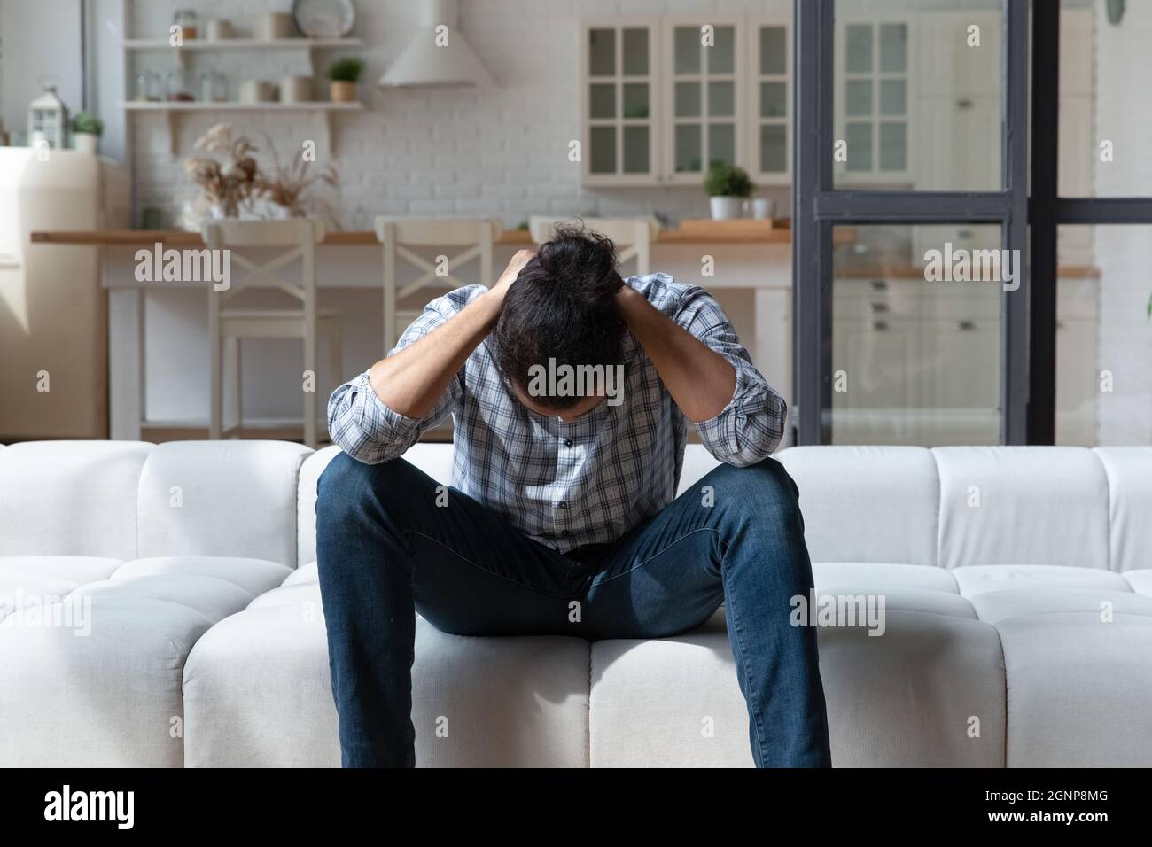 Deprimierter afroamerikanischer Mann, der über Probleme nachdenkt und auf der Couch sitzt Stockfoto