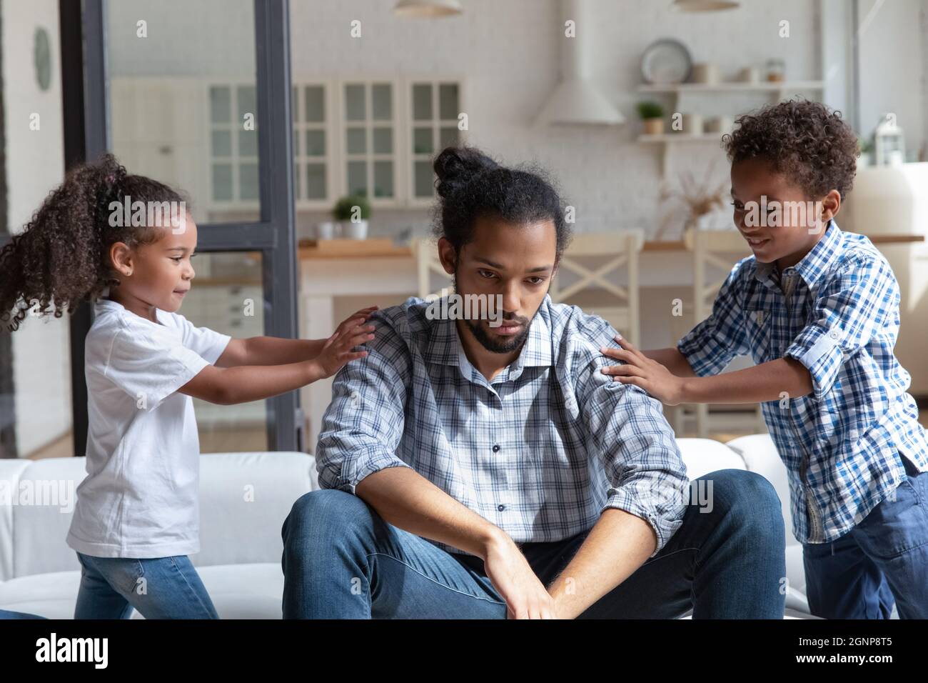 Unglücklicher afroamerikanischer Vater ignoriert laute Kinder und fühlt sich erschöpft Stockfoto