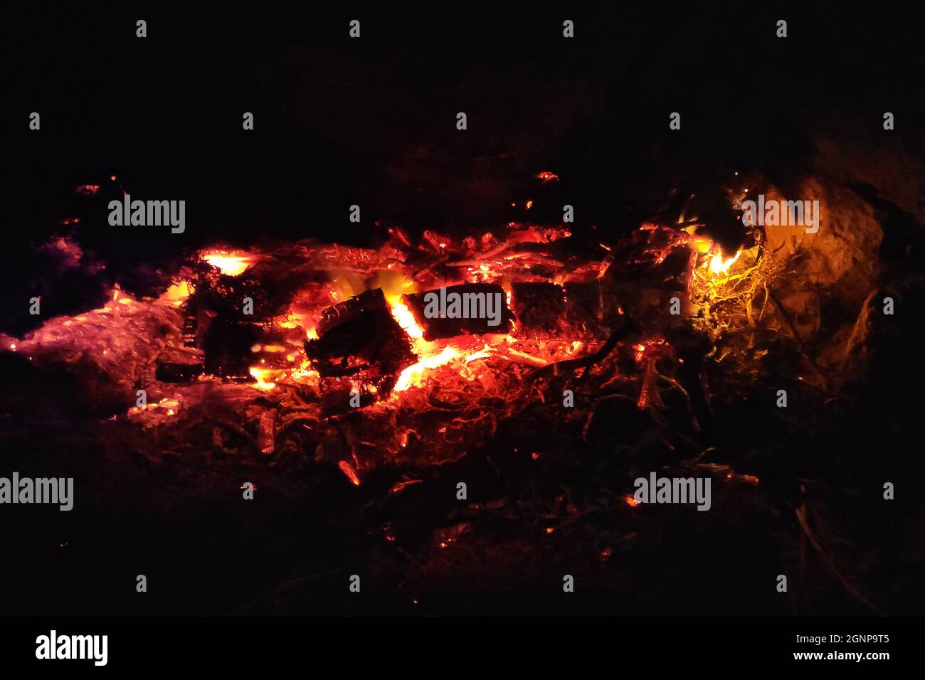 Nahaufnahme der Glut eines noch glühenden Feuers in einem Steinkamin. Stockfoto