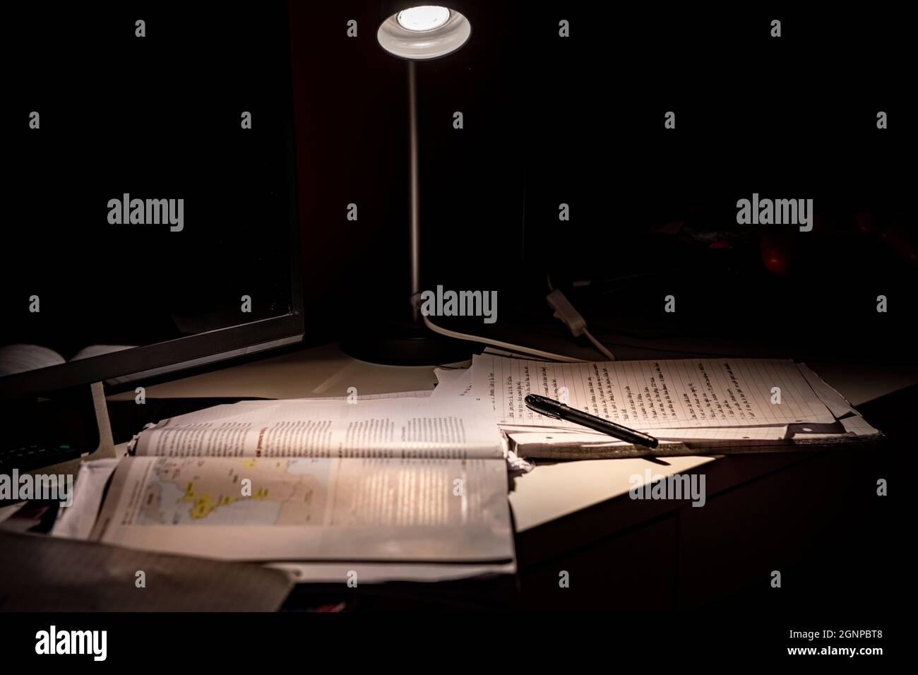 Eine Anglepoise-Lampe und die Revision eines Studenten für Prüfungen Stockfoto