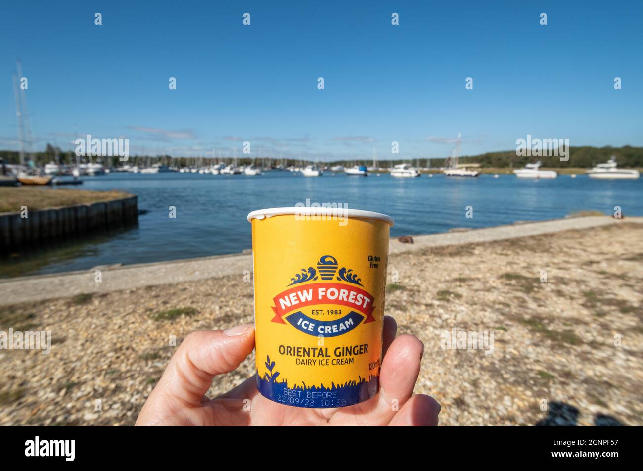 Essen Sie eine Wanne New Forest Ice Cream bei Bucklers Hard mit Blick auf den Beaulieu River und Boote an einem sonnigen Tag, Hampshire, Großbritannien Stockfoto