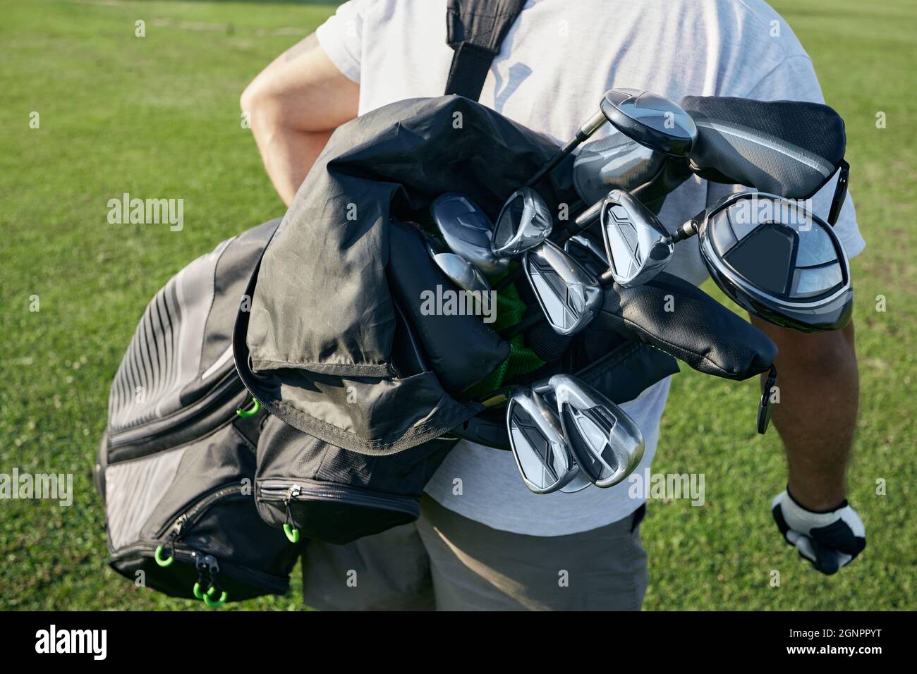 Golfer mit Tragetasche hinter sich mit verschiedenen Golfschlägern auf dem Golfplatz, während Sie im Freien Golf spielen, aus nächster Nähe Stockfoto