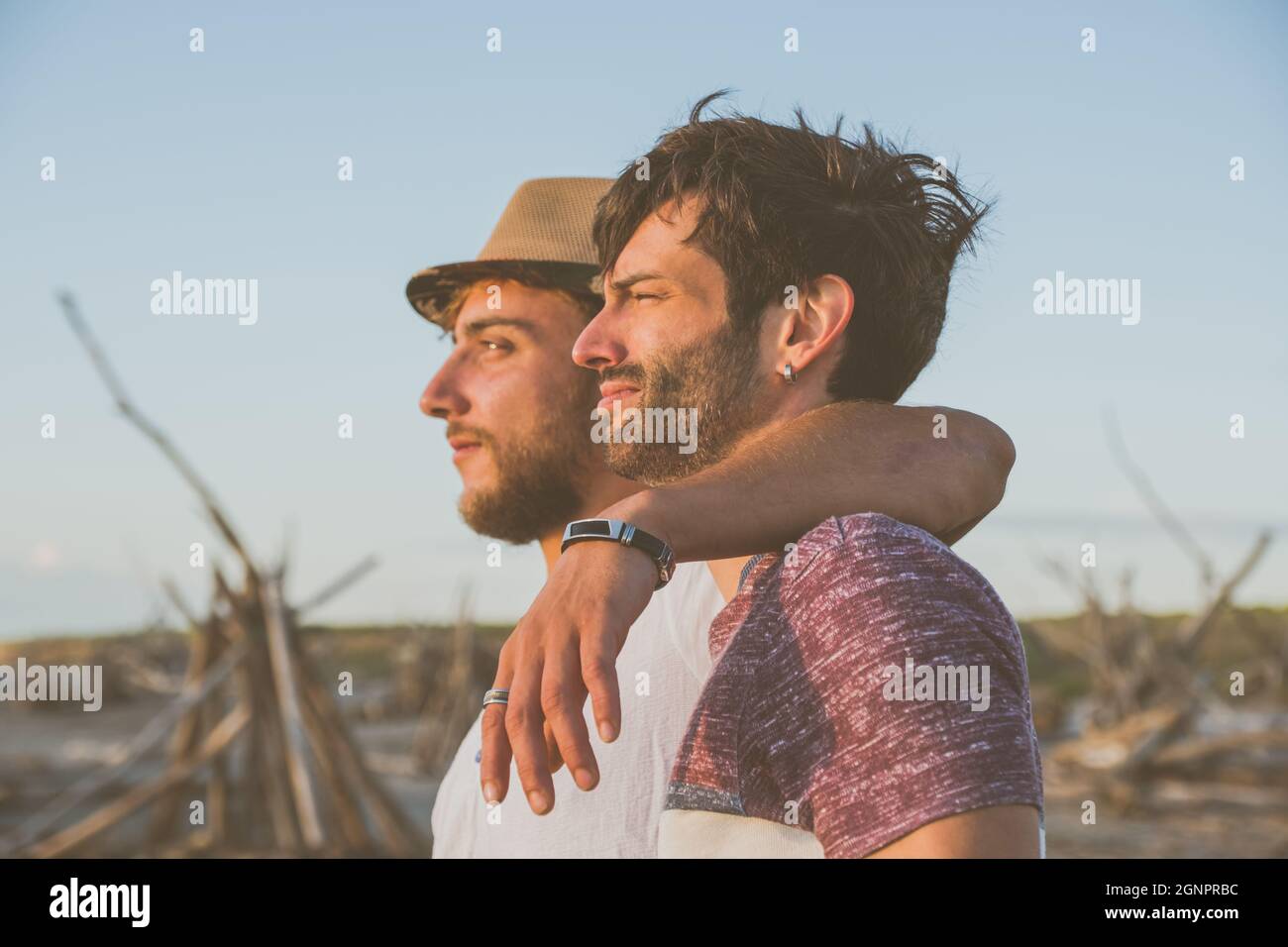 Zwei Freunde umarmen sich gegenseitig und schauen sich den Sonnenuntergang am Strand an. Freundschaft und Liebeskonzept6 Stockfoto