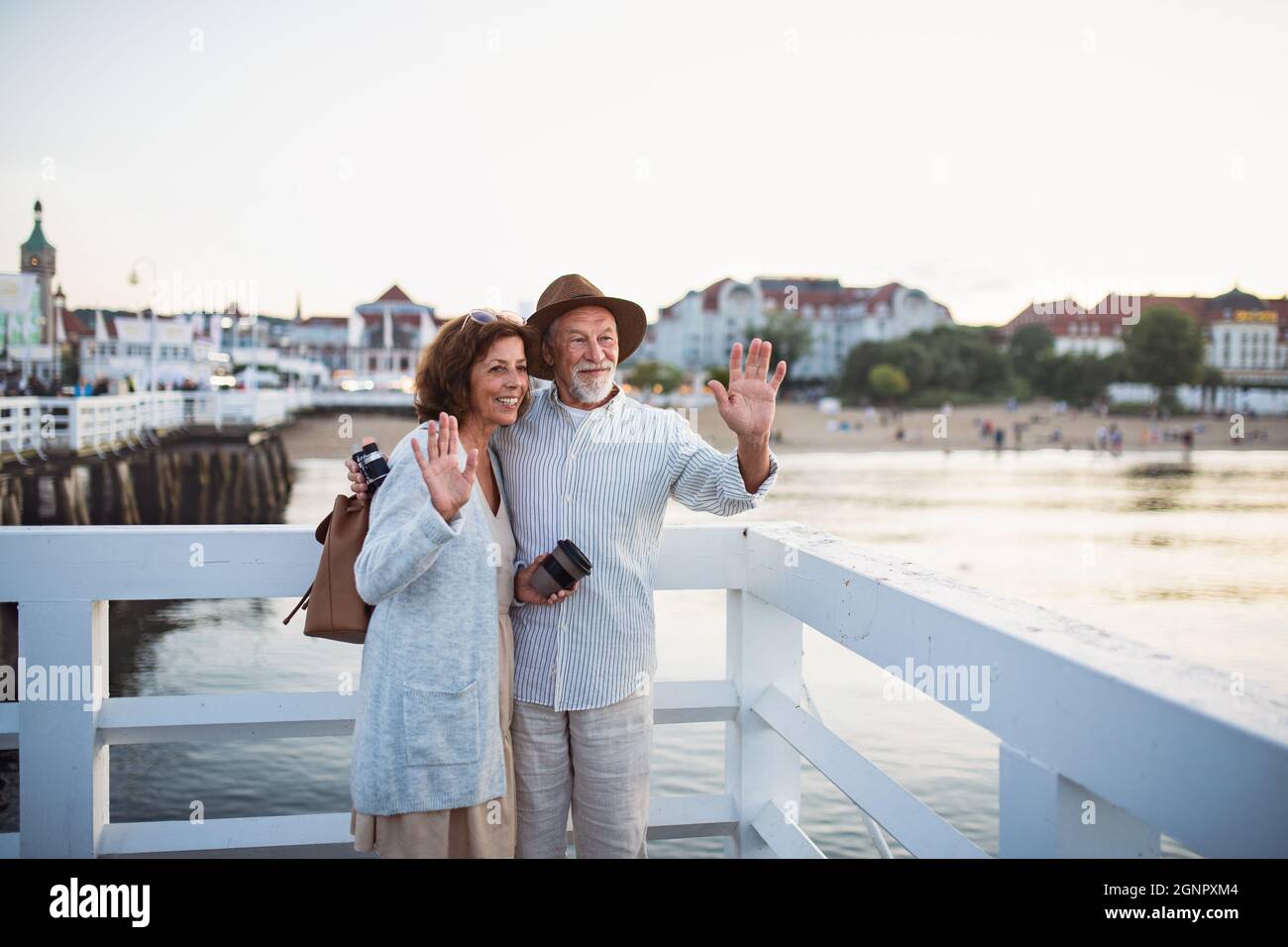 Glückliches Seniorenpaar, das auf dem Pier am Meer im Freien wabt und sich für Fotos posiert. Stockfoto