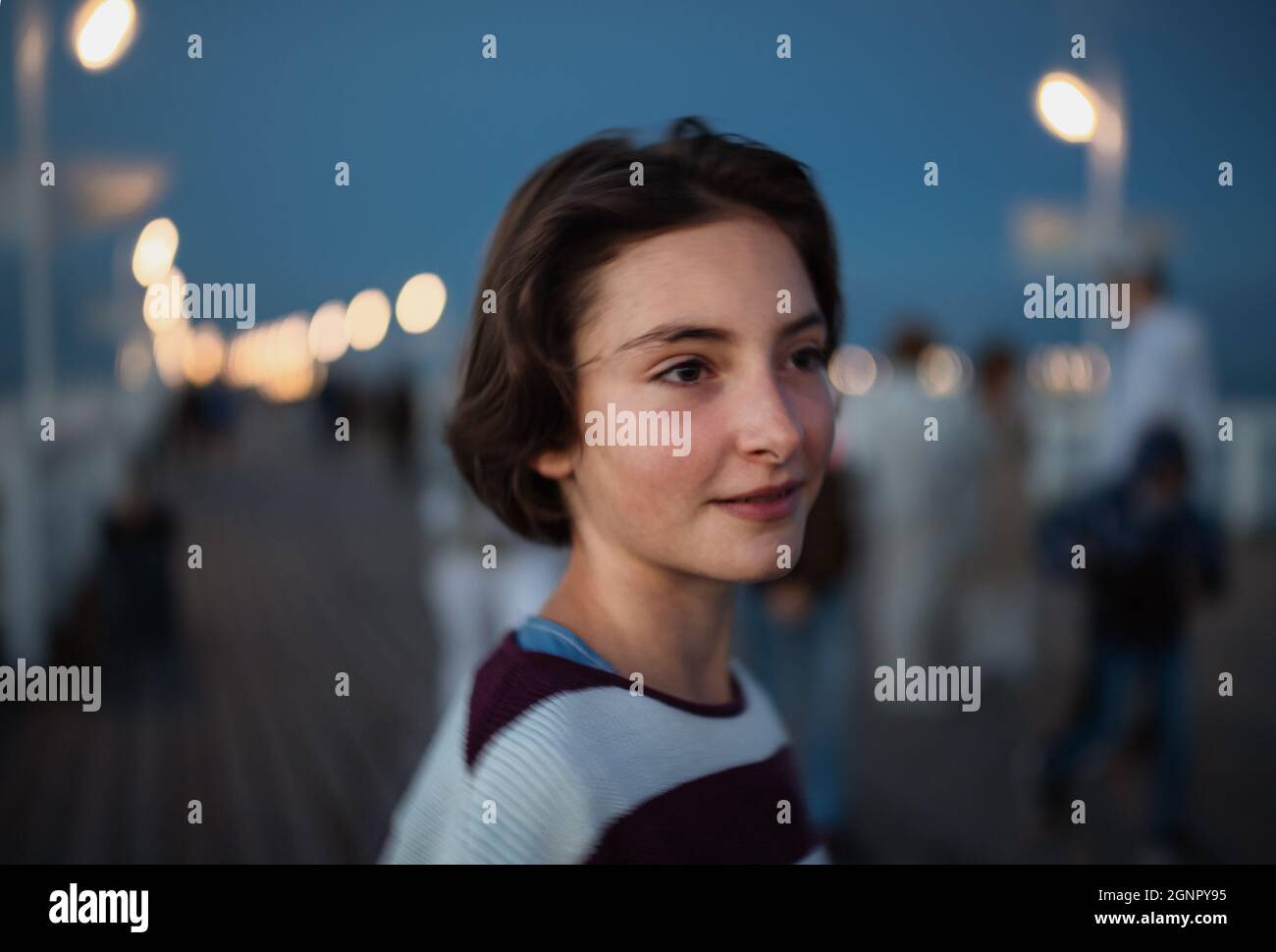 Porträt eines jungen Mädchens, das in der Abenddämmerung auf dem Pier am Meer im Freien auf der Seite liegt, Urlaubskonzept. Stockfoto