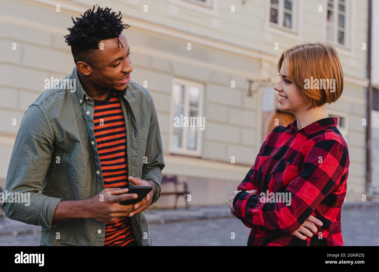 Junger Mann, der draußen auf der Straße mit Freundinnen spricht. Stockfoto