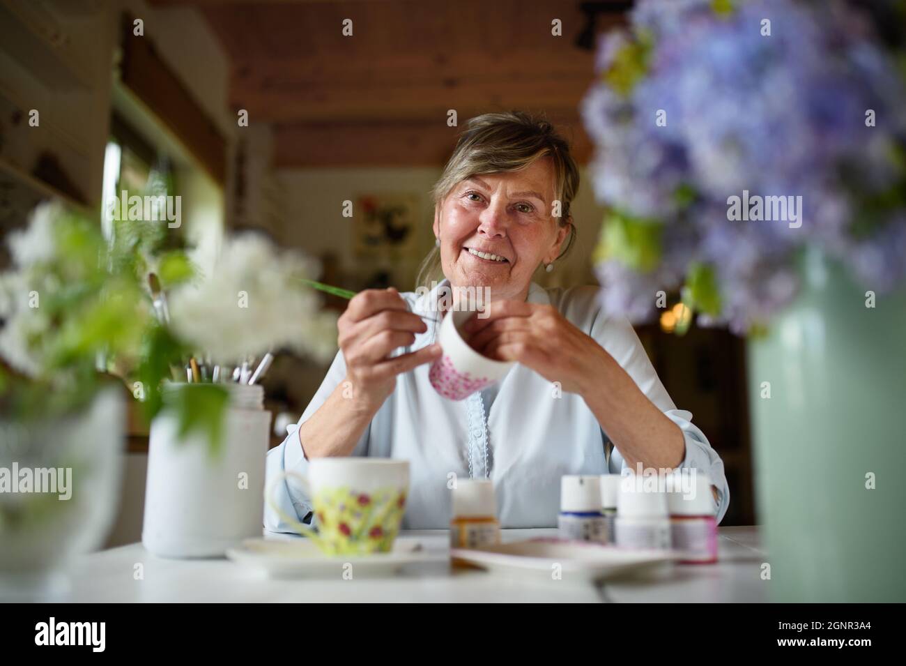 Low-Winkel-Ansicht der glücklichen Senior-Künstlerin Frau Malerei kermaischen Tasse, Kunstfertigkeit Konzept. Stockfoto