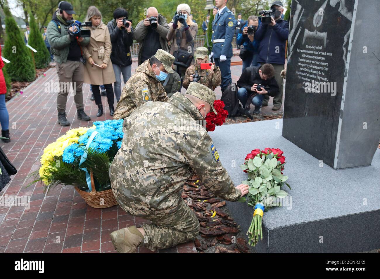 KHARKIV, UKRAINE - 25. SEPTEMBER 2021 - Menschen legen Blumen an das temporäre Gedenkschild, das an der Absturzstelle des TRAINERFLUGZEUGS AN-26 in der Nähe angebracht ist Stockfoto