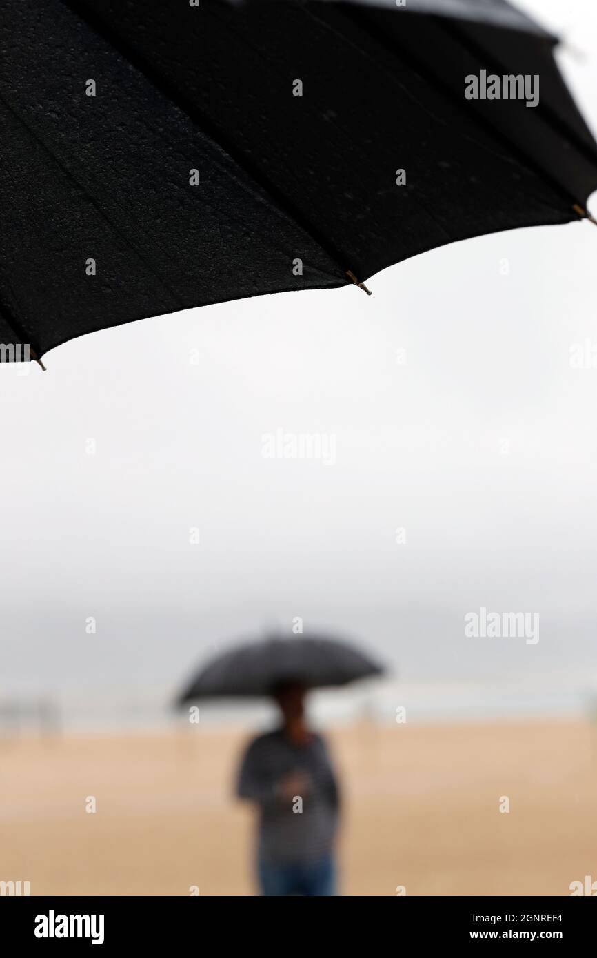 Menschen, die mit Regenschirm in regnerischen Tag Szene zu Fuß. Nazare. Portugal. Stockfoto