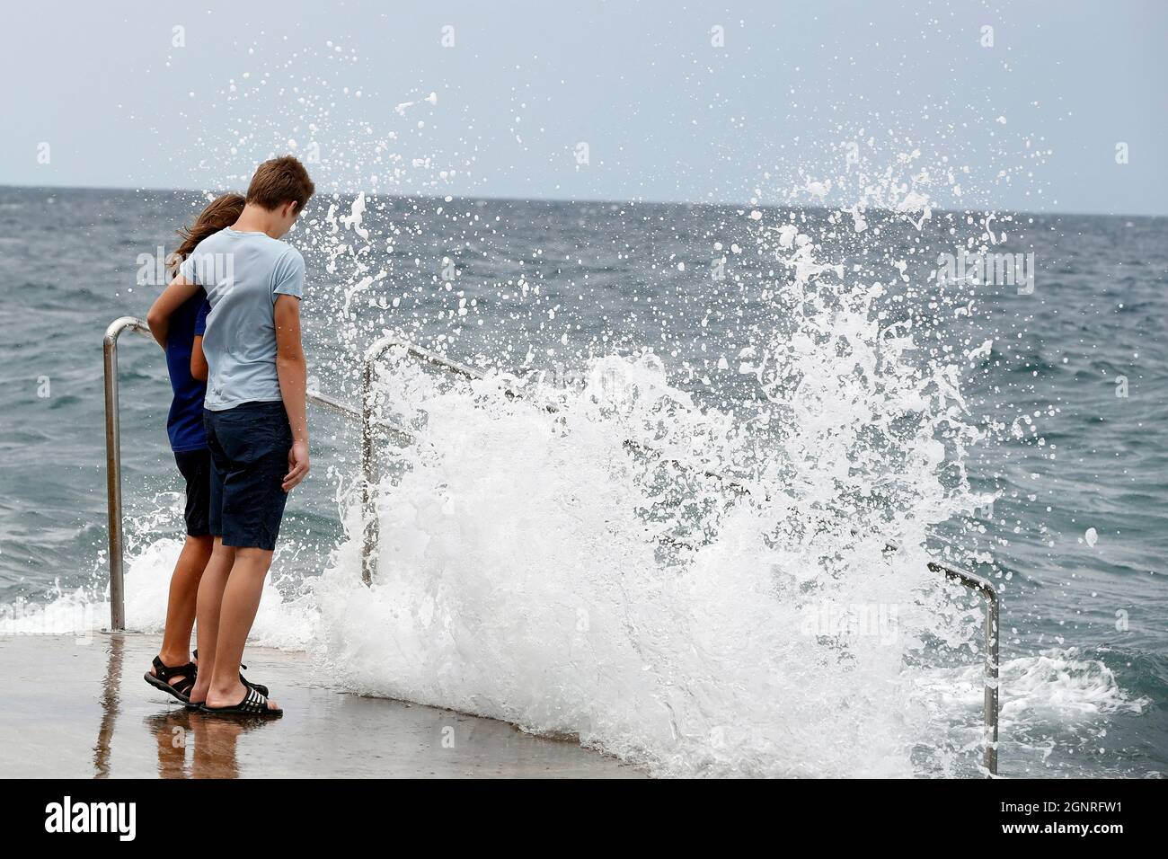 Junges Paar, das auf die brechenden Wellen schaut. Piran. Slowenien. Stockfoto Junges Paar, das auf die brechenden Wellen schaut. Piran. Slowenien. Stockfoto
