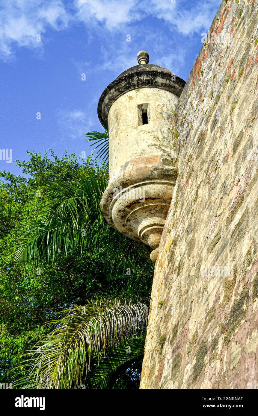 Ein Wachturm und eine Steinmauer der historischen Stadtmauer ragt über einem öffentlichen Gehweg des Old San Juan. Speicherplatz kopieren Stockfoto