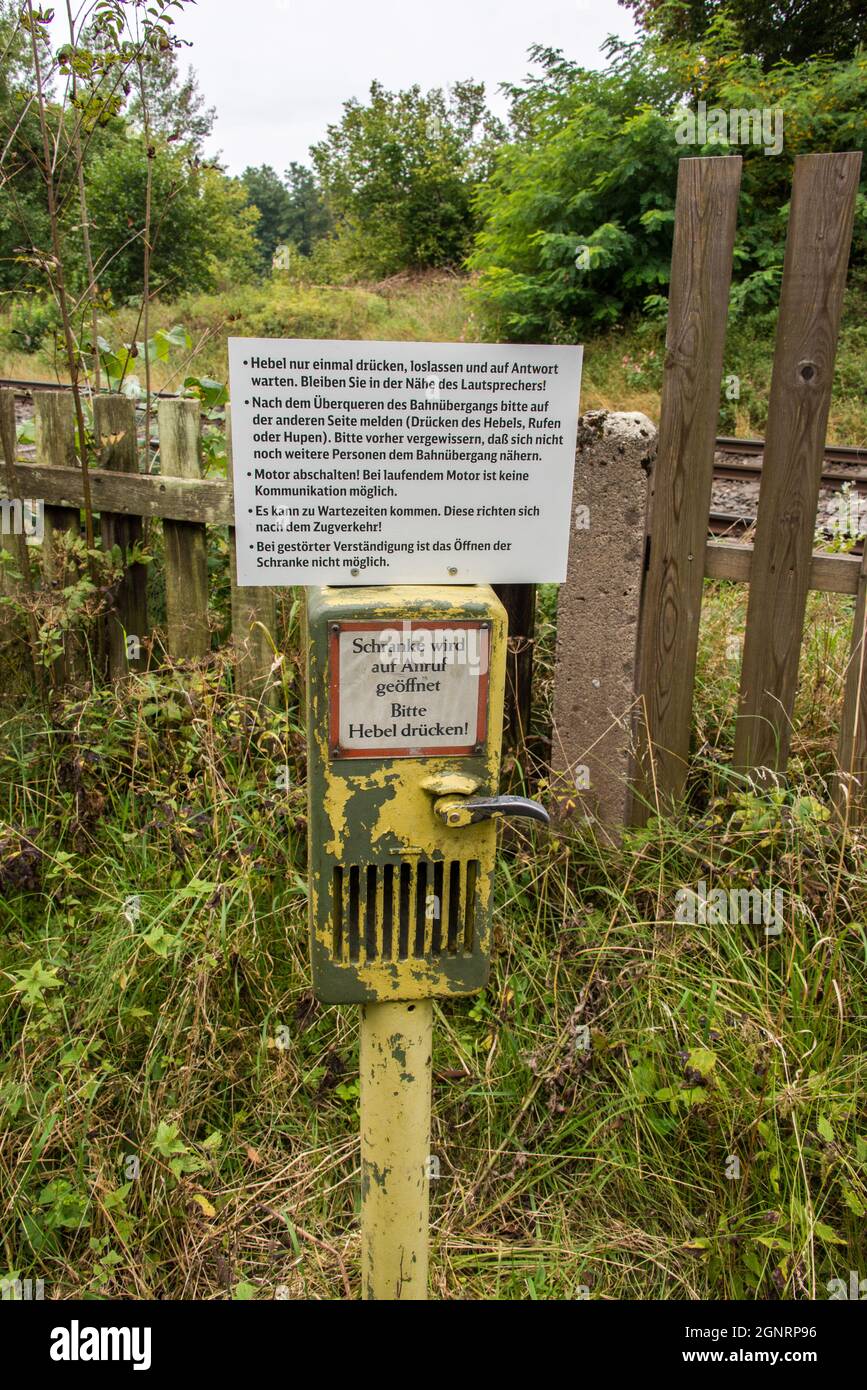 Rufnummernbox an einem abrufbereiten Bahnübergangstor für Wanderer, Radfahrer und Landverkehr in einer Waldregion Nordbayern. Stockfoto