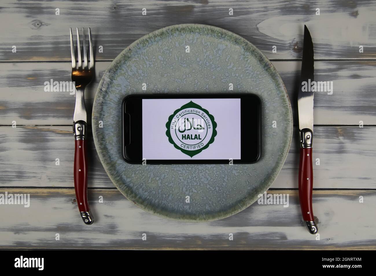 Viersen, Deutschland - Juni 9. 2021: Nahaufnahme des Smartphones mit Logo-Schriftzug von Halal-Zertifizierungsdiensten auf Teller mit Besteck (Schwerpunkt auf Mitte) Stockfoto