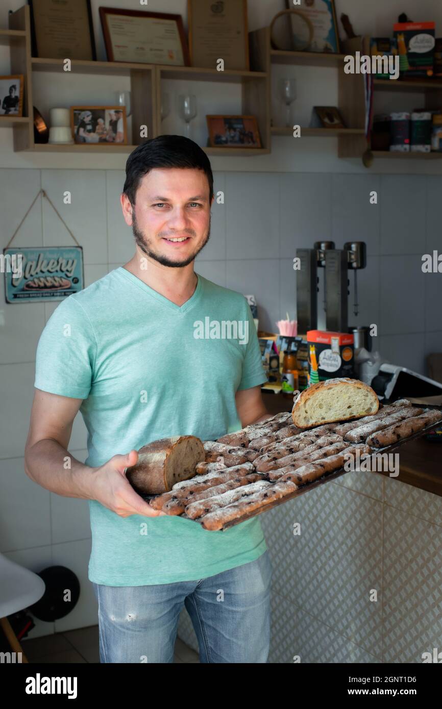 Der junge Bäcker zeigt sein handwerkliches Sauerteig-Brot. Erfolgskonzept, endgültig. Stockfoto
