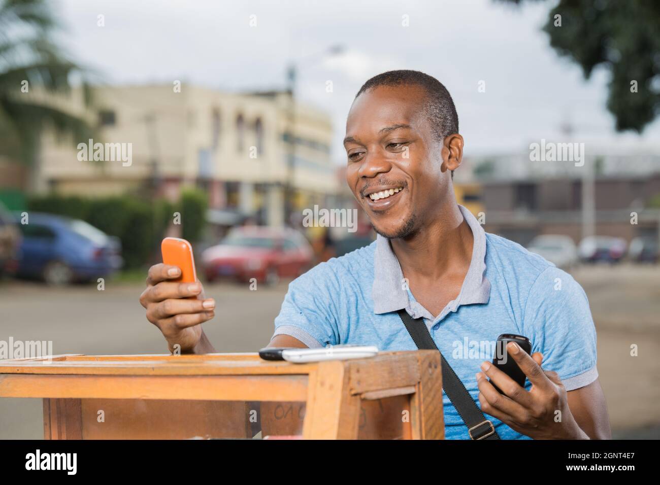 jeune travailleur souriant avec des téléphones en mains Stockfoto