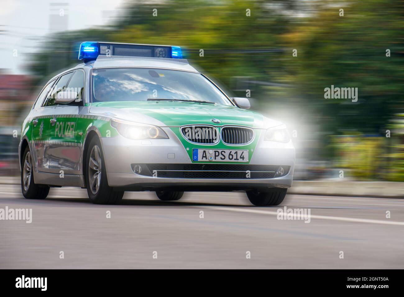 Ein Polizeiauto fährt mit hoher Geschwindigkeit und Blaulicht durch die Stadt Augsburg Stockfoto