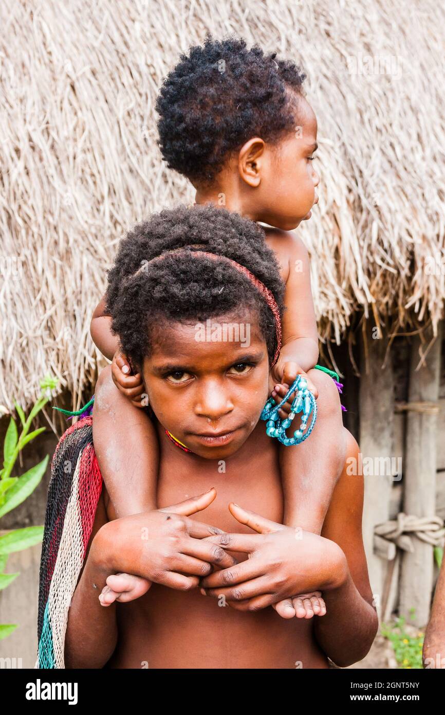 Wamena, Indonesien - 9. Januar 2010: Kinder des Dani-Stammes stehen in nea Strohhäusern, Papua-Neuguinea. Stockfoto