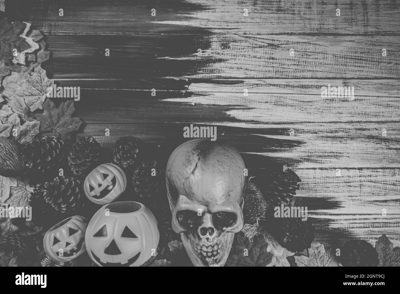Halloween menschlicher Totenkopf, Halloween Ahornblätter auf einem alten Holztisch vor schwarzem Hintergrund mit freiem Platz für Text. Halloween-Konzepte. Glücklich Stockfoto