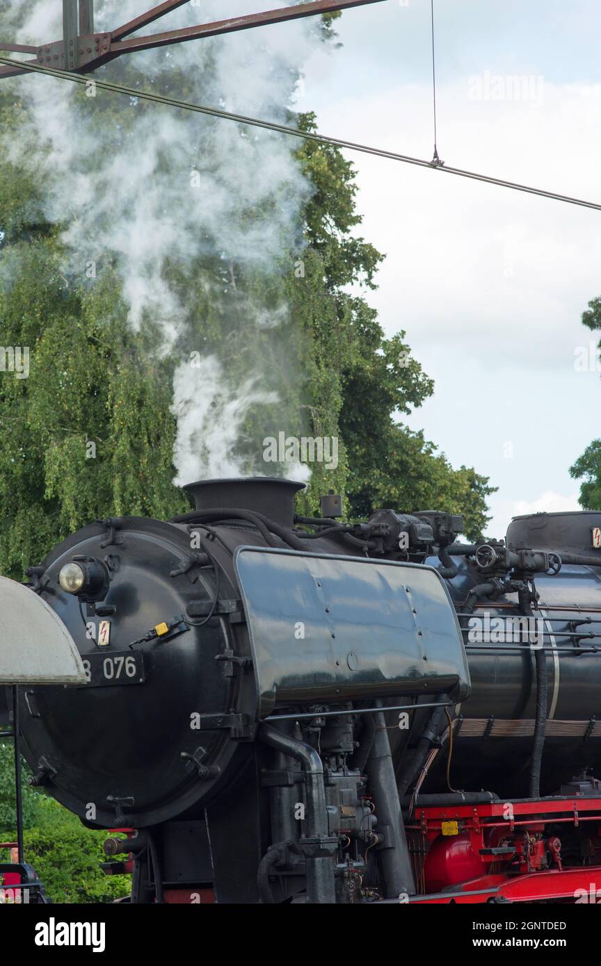 Detail einer alten historischen Dampflokomotive mit Rauch am Bahnhof