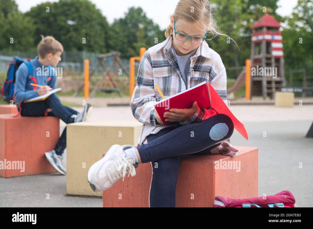 Nette Teenager Kinder lernen oder machen Hausaufgaben auf dem Schulhof während der Pause vor dem Unterricht Stockfoto