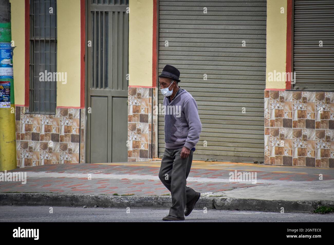 Ein älterer Mann überquert die Straße, als er am 15. August 2021 in Cumbal - Nariño, Kolumbien, eine Gesichtsmaske gegen COVID-19 trägt. Stockfoto