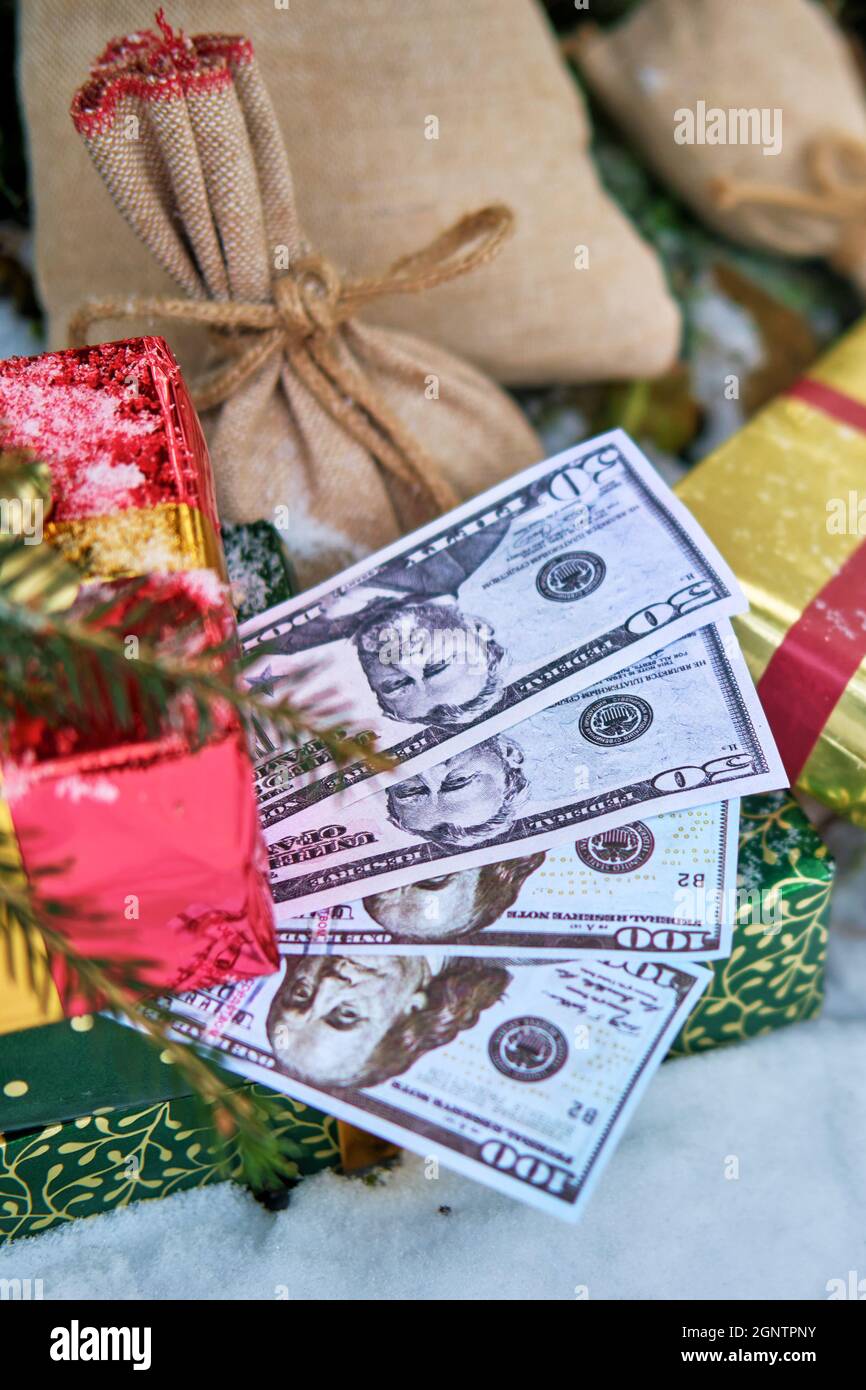 Geschenke in roten Schachteln und Geld in US-Dollar liegen im neuen Jahr unter dem Weihnachtsbaum Stockfoto