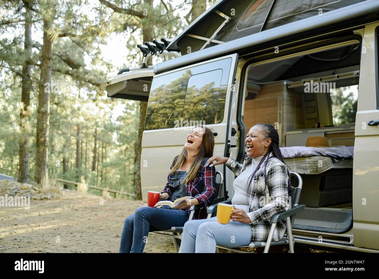 Multirassische Reisende Frauen, die in der Nähe des Campers lachen Stockfoto