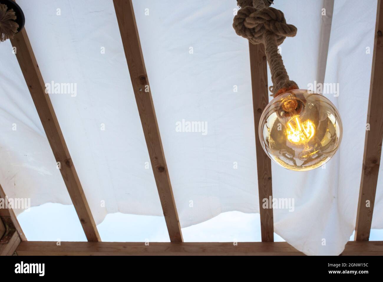 Seil Glühbirne über Leinwand Pergola Abdeckung. Low-Angle-Ansicht Stockfoto