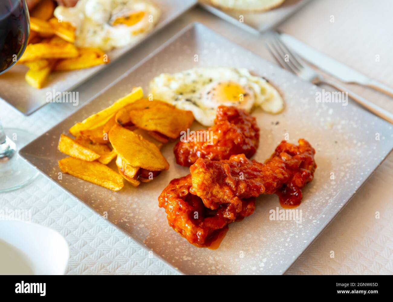 Gebackene Kartoffeln mit Huhn in Sauce und Spiegelei auf dem Teller Stockfoto