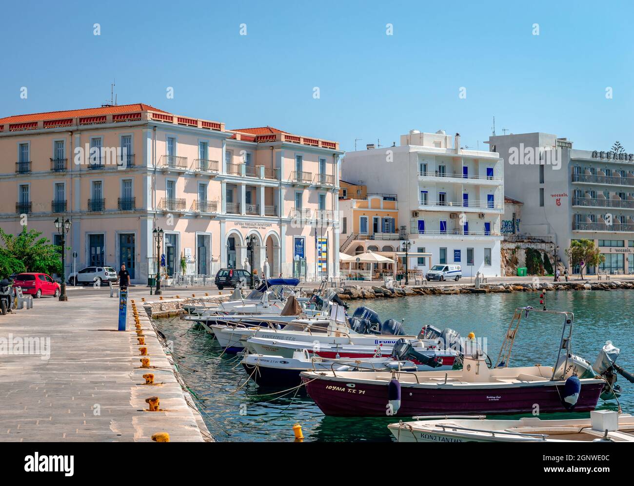 Die Uferpromenade von Tinos mit neoklassizistischen Gebäuden am Meer und vielen Booten, an einem sonnigen Morgen. Tinos ist eine griechische Insel in der Ägäis. Stockfoto
