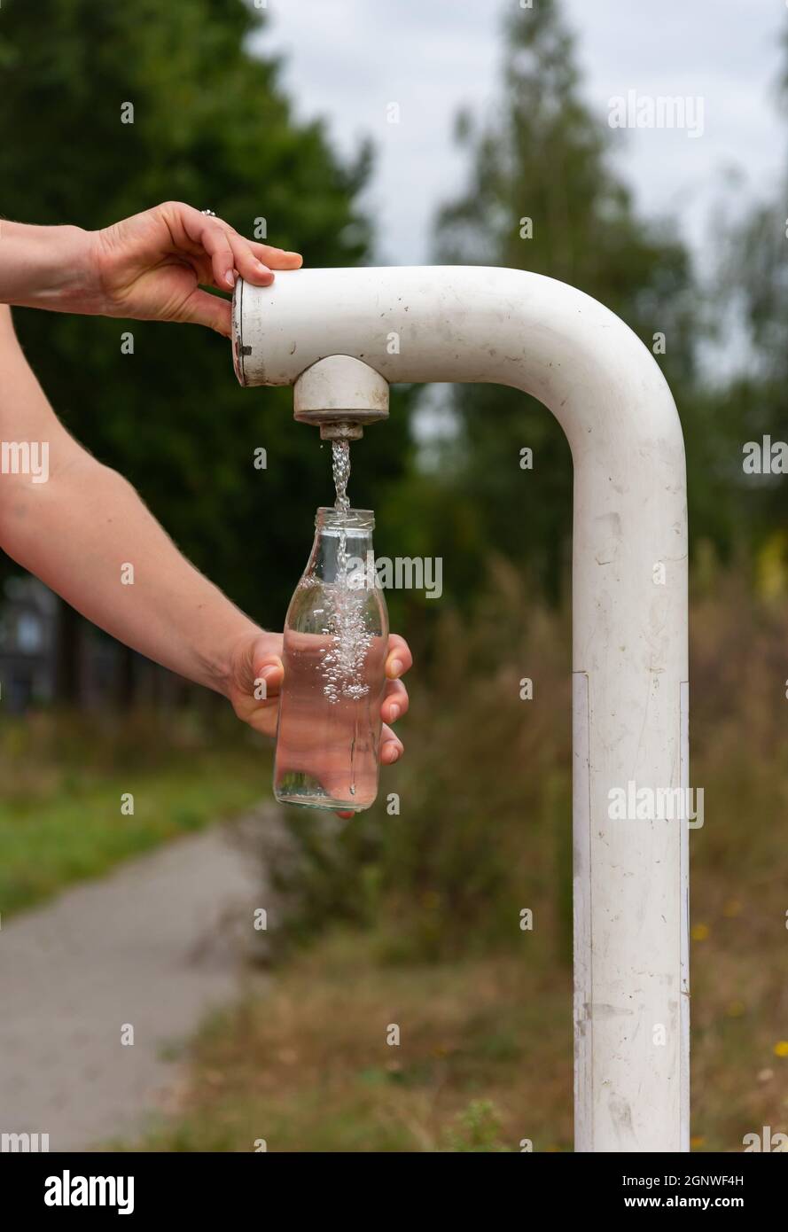 Nahaufnahme des weiblichen Handfüllens der Glasflasche mit Wasser aus einem kostenlosen öffentlichen Wasserhahn Stockfoto