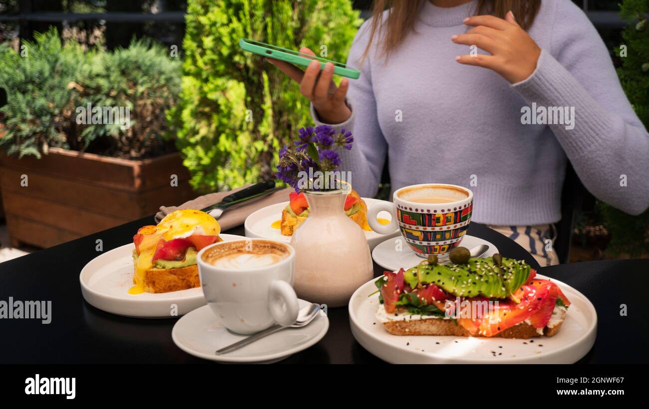 Wunderschön dekorierter Toast mit Lachs und Avocado, Ei benedict und Cappuccino das Frühstück ist die Tageszeit für Meetings Stockfoto