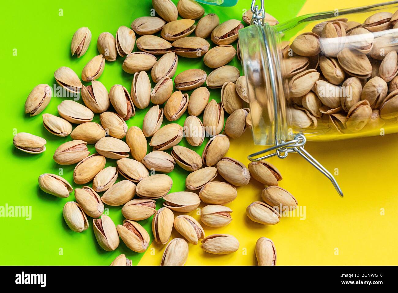 Gebratene Pistazien mit Salz, das aus einem Glas in der Nähe verschüttet wurde Stockfoto