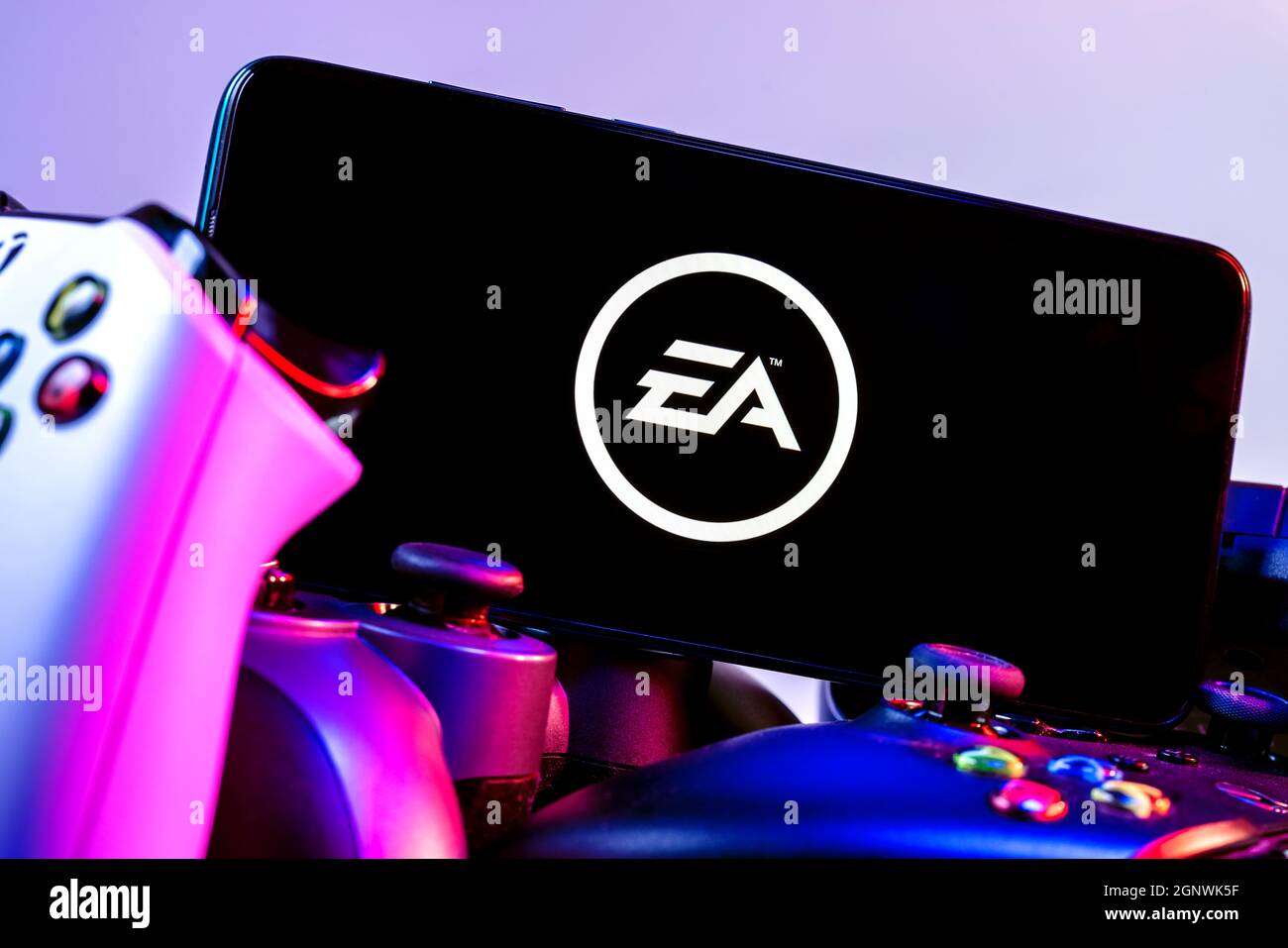 Ein Smartphone mit dem Electronic Arts-Logo auf dem Bildschirm auf dem Stapel der Gamepads. Stockfoto