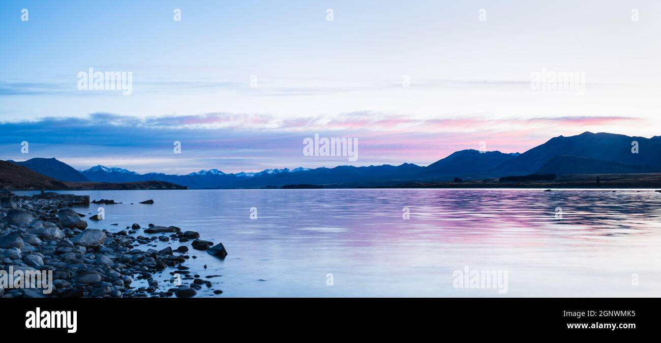 Panoramablick auf den Lake Tekapo mit den südlichen Alpen im Hintergrund bei Sonnenaufgang, Mackenzie Country, South Island. Stockfoto