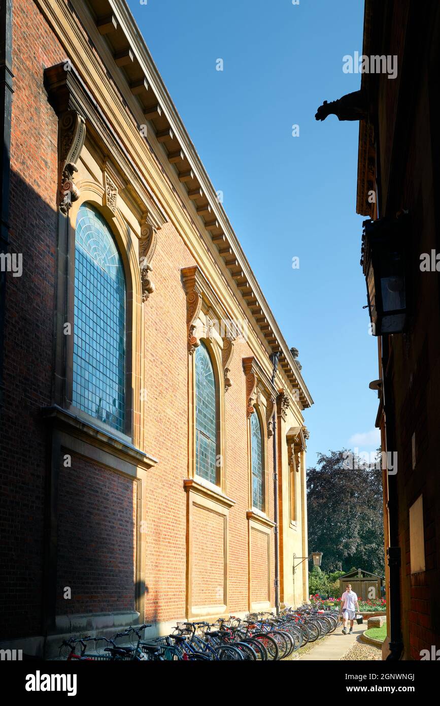 An einem sonnigen Sommertag geht ein Mann an Fahrrädern vorbei, die vor der Bibliothek des Pembroke College der Universität Cambridge, England, geparkt sind. Stockfoto