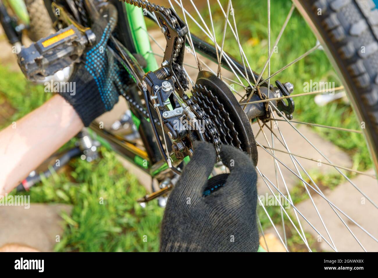 Fahrradmechaniker Mann repariert Fahrrad in Fahrradwerkstatt, im Freien. Die Hand des Fahrradfahrers untersucht, repariert modernes Zyklenübertragungssystem. Fahrrad ma Stockfoto