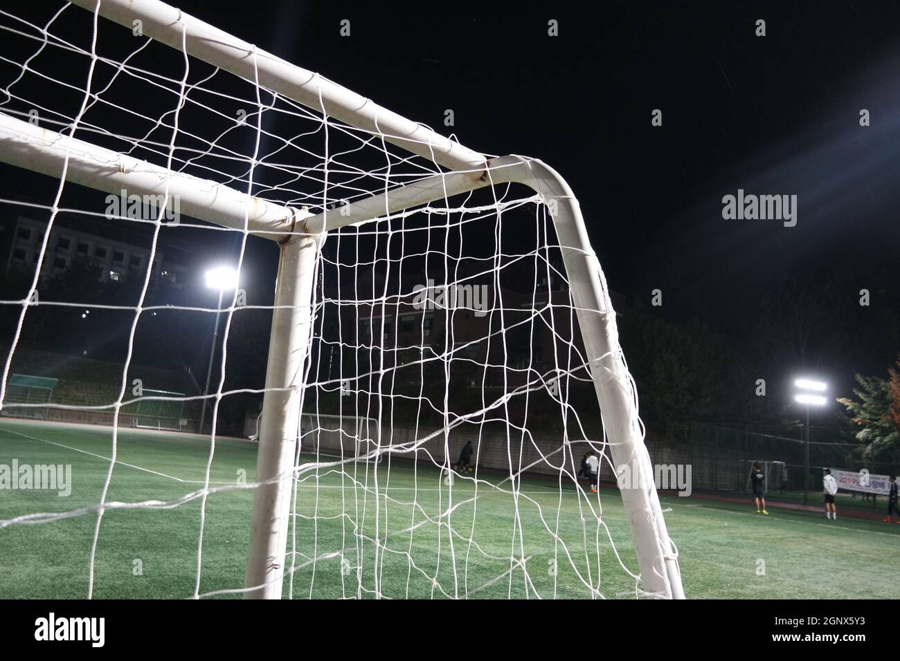 Nachtansicht eines Fußballtor-Netzes unter Flutlicht. Nahaufnahme des Tornetzes auf einem Fußballplatz Stockfoto
