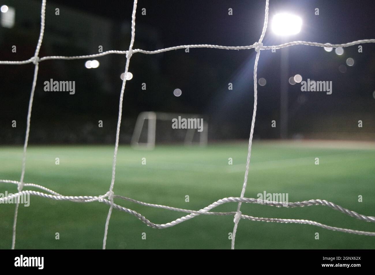 Nachtansicht eines Fußballtor-Netzes unter Flutlicht. Nahaufnahme des Tornetzes auf einem Fußballplatz Stockfoto