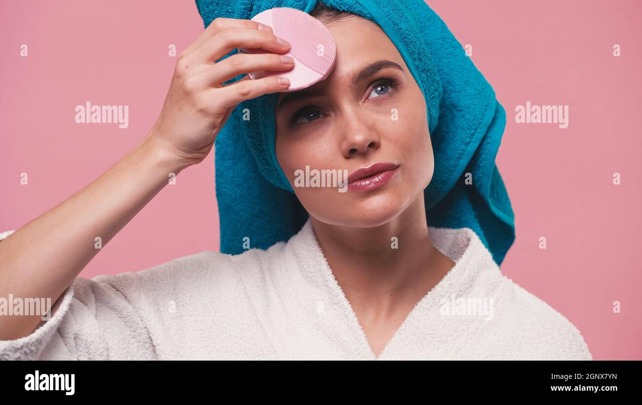 Hübsche Frau mit Silikon Gesichtsreiniger isoliert auf rosa Stockfoto
