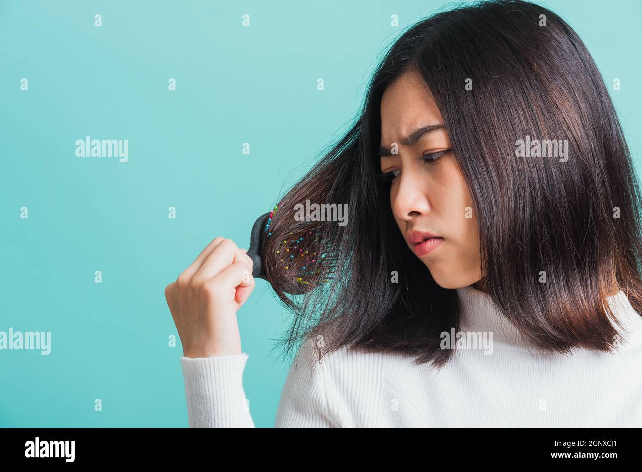 Junge schöne asiatische Frau aufgeregt mit einem Kamm und Problem Haar, Porträt weiblich schockiert leiden an Haarausfall Problem, Studio erschossen auf einem BL isoliert Stockfoto