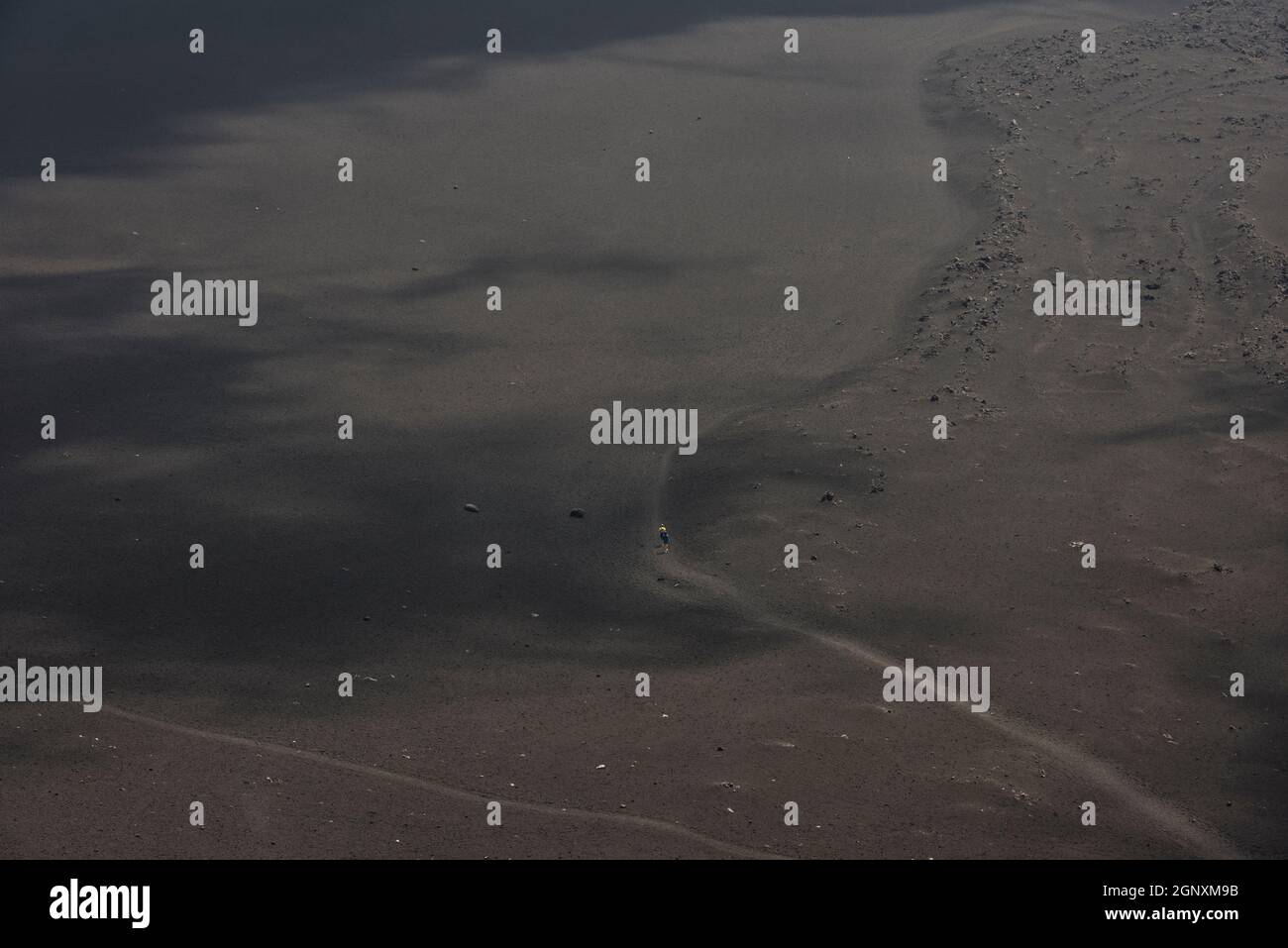 Zwei Wanderer überqueren eine riesige Ebene aus schwarzer Vulkanasche an den Hängen des Ätna, Sizilien, Italien Stockfoto