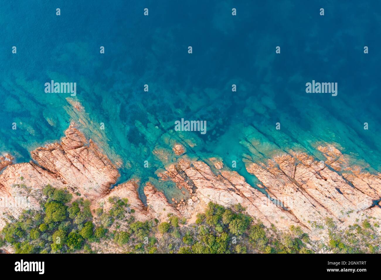 Blick von oben, atemberaubende Luftaufnahme einer grünen und felsigen Küste, die von einem türkisfarbenen, kristallklaren Wasser umspült wird. Liscia Ruja, Costa Smeralda, Sardinien Stockfoto
