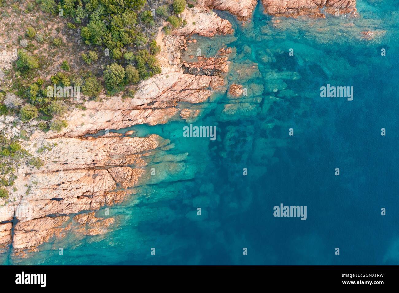 Blick von oben, atemberaubende Luftaufnahme einer grünen und felsigen Küste, die von einem türkisfarbenen, kristallklaren Wasser umspült wird. Liscia Ruja, Costa Smeralda, Sardinien Stockfoto