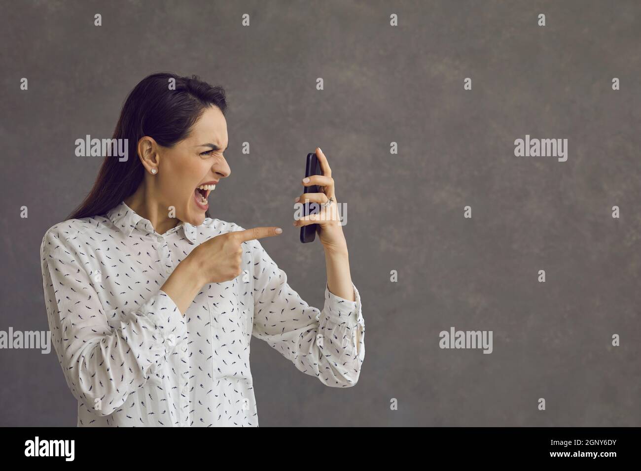 Wütend aggressive Frau nervös schreiend Blick vor Hass auf Handy-Bildschirm. Stockfoto