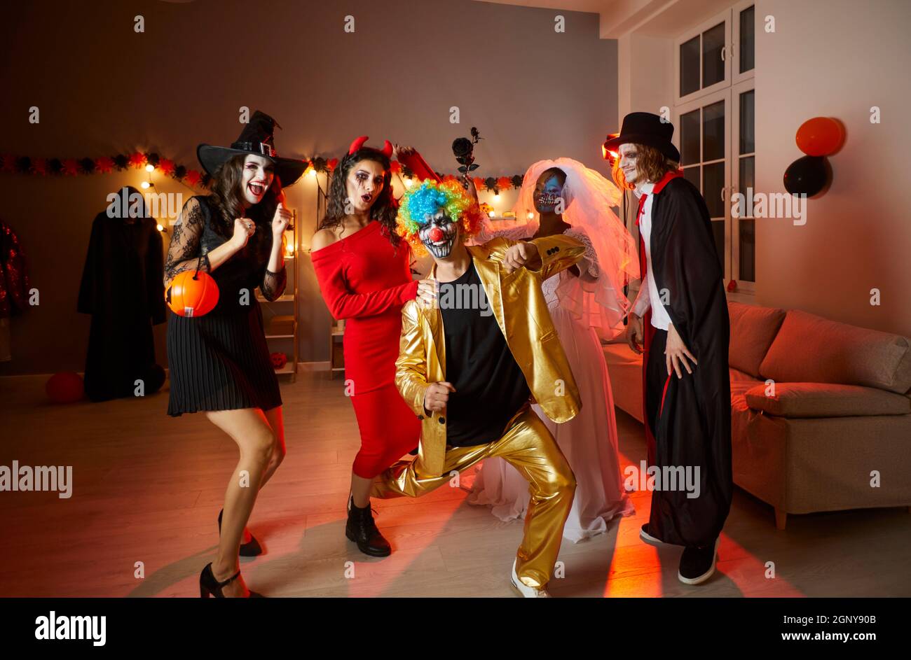 Eine Gruppe von glücklichen jungen Freunden in Kostümen, die sich auf einer Halloween-Party zu Hause amüsieren Stockfoto